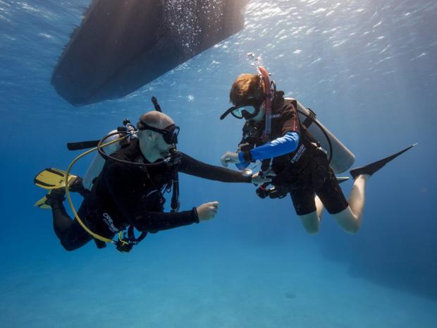 Two divers underwater near a boat