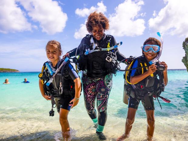 People walking along the beach holding snorkel gear