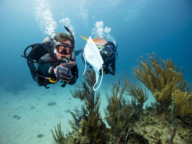 Two divers picking up trash in the ocean.