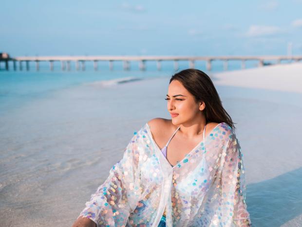 Sonakshi Sinha sitting on the beach.