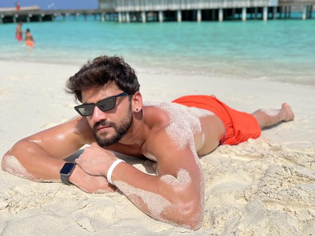 Zaheer Iqbal laying down on the beach.