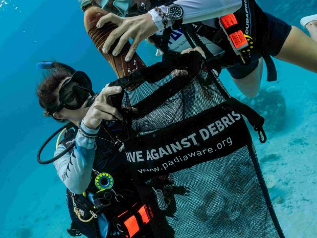 Two scuba divers helping the ocean by collecting debris
