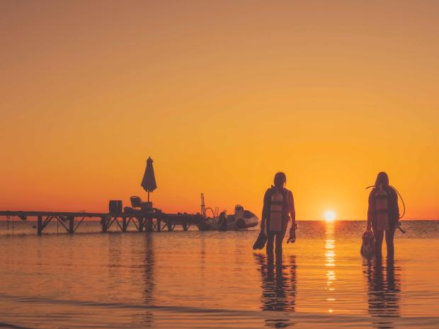 Divers preparing for a dive during a sunset