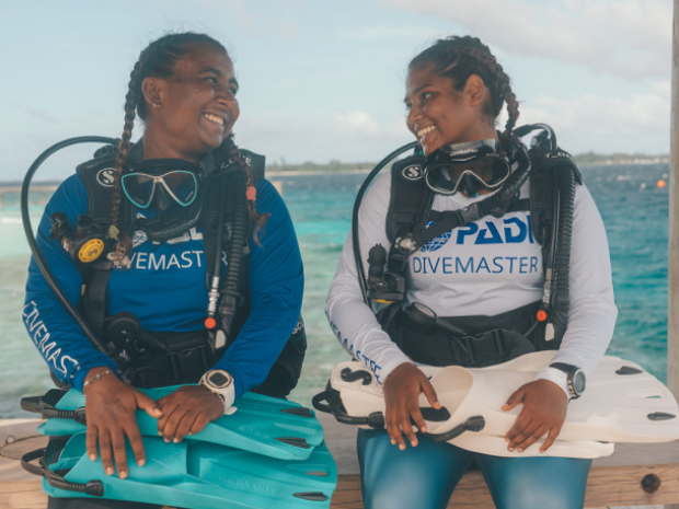 A couple divers in PADI gear smiling at each other.