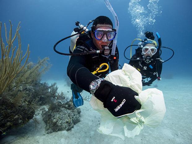 Divers picking up trash in sea.