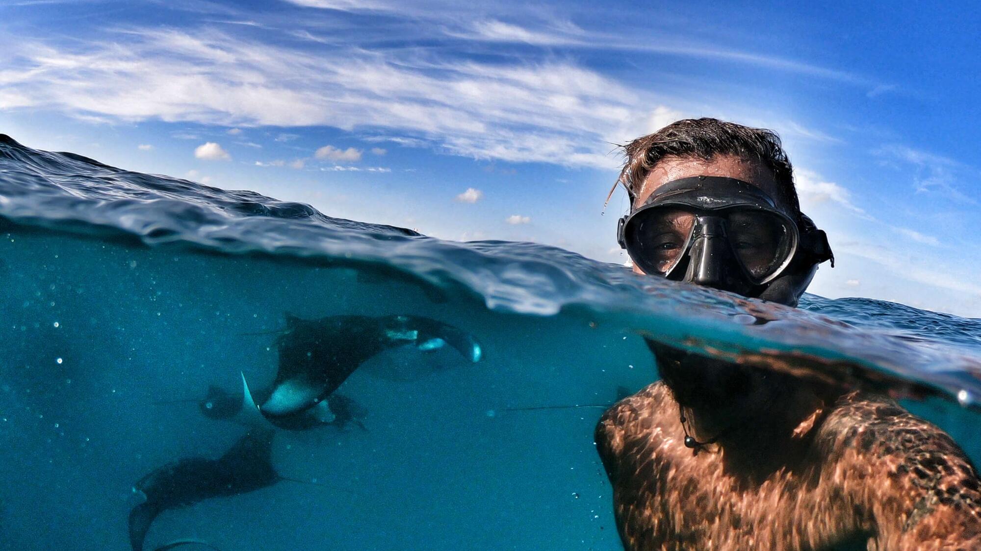 Siraj Ahmed taking a selfie on the water surface with manta rays