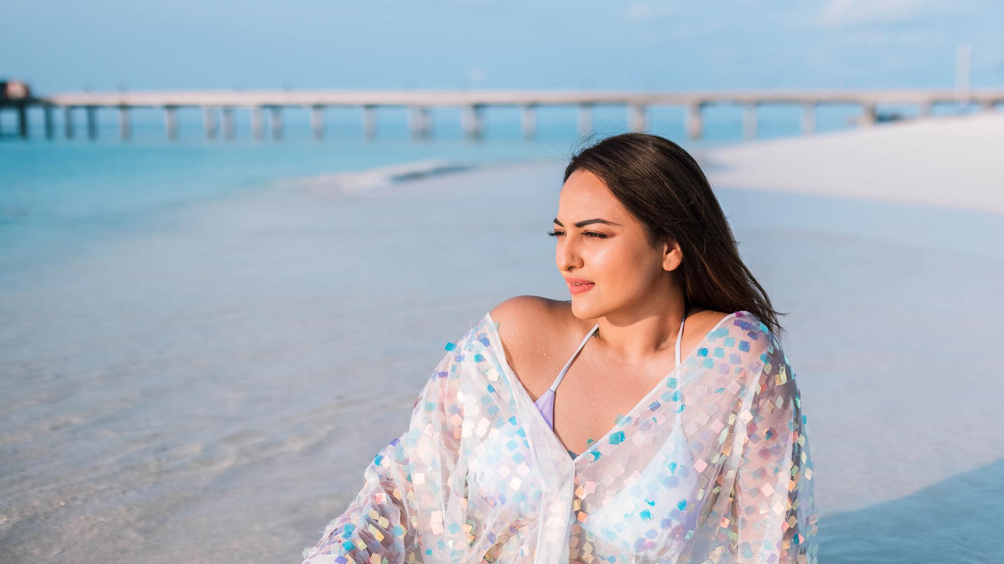 Sonakshi Sinha sitting on the beach.