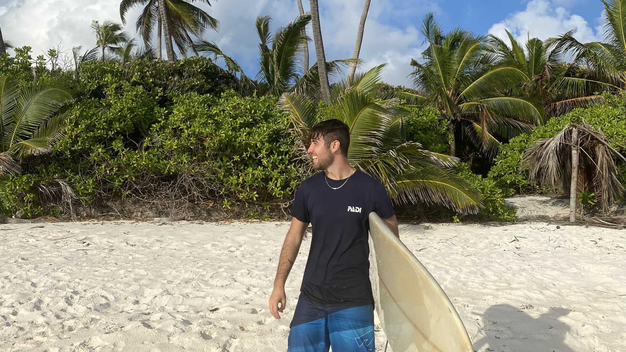 PADI AmbassaDiver Giosue Reale on the beach with a surfboard.
